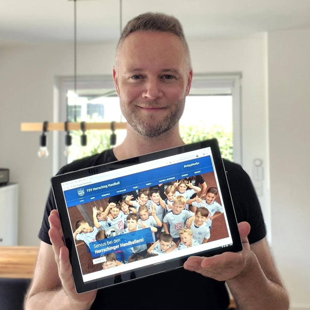 Portrait von Dominik Huber von lakeSITE webdesign vom Ammersee mit Tablet, welches die TSV Herrsching Handball Website zeigt